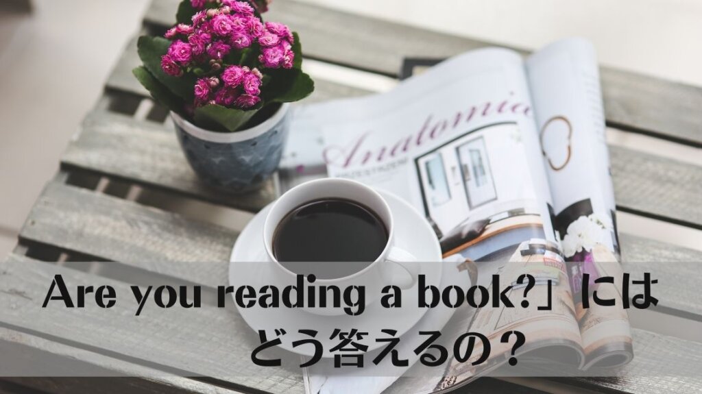 木製の台の上に鉢植えに入ったピンク色の花とページの中ほどで開かれた雑誌、そしてその雑誌が閉じてしまわないように雑誌の上にコーヒーの入ったコーヒーカップが置かれています。